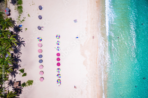 Top view of beach with colorful umbrellas and people bathing in El Nido, Palawan, Philippines.