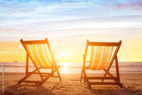 beach tourism  holiday background with couple of deck chairs at sunset