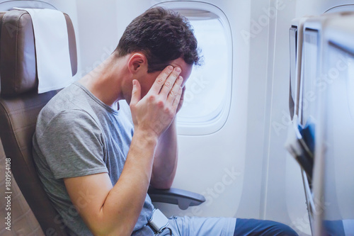 headache in the airplane, man passenger afraid and feeling bad during the flight in plane photo