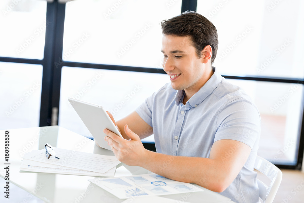 Young handsome businessman using his touchpad sitting in office