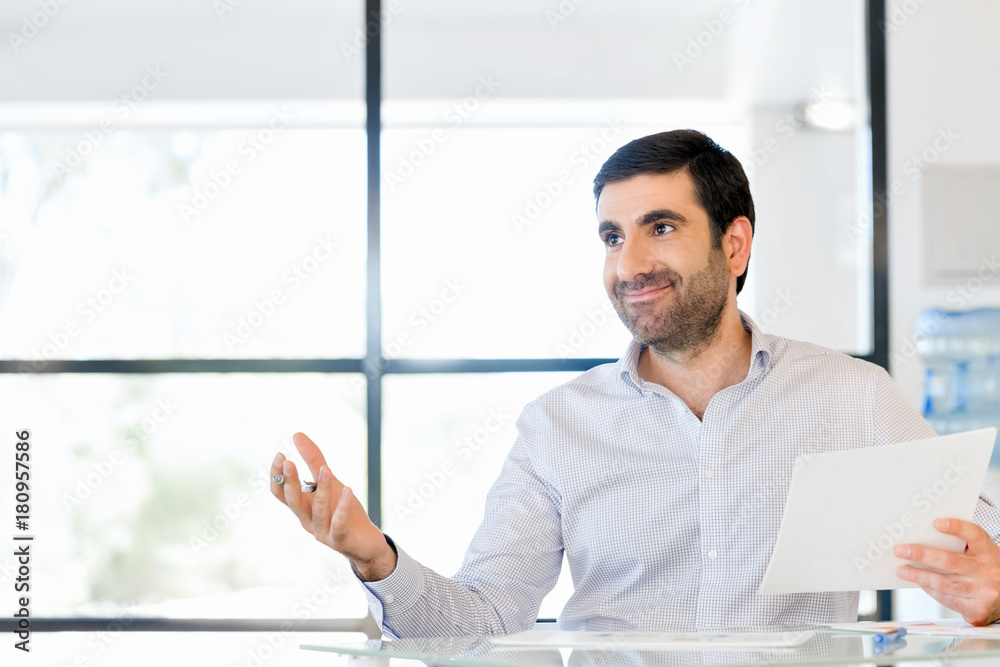 Handsome young man holding paper in office