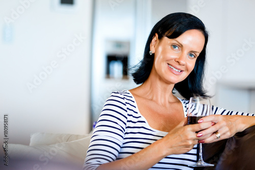 Beautiful young woman holding glass with red wine