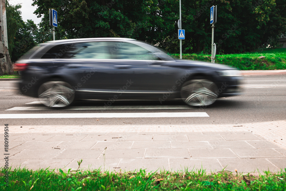 A black machine at high speed crosses a pedestrian crossing, a motion blur effect