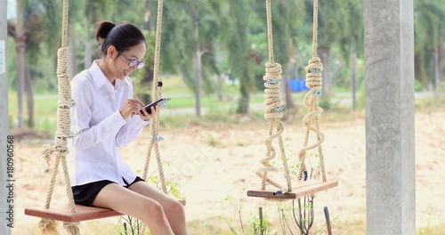 Happy asian womanhand holding mobile phone on swing chair with smile face. photo
