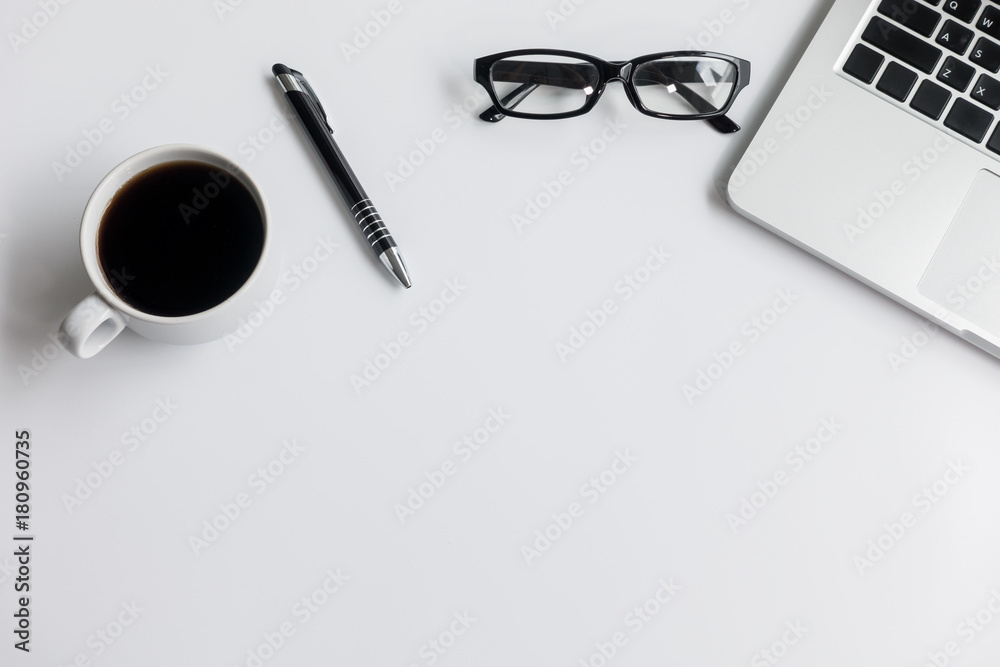 White office desk table with blank notebook, laptop computer, cup of coffee and supplies. Top view, flat lay. White office desk table with blank notebook, laptop computer, cup of coffee and supplies. Top view, flat lay.