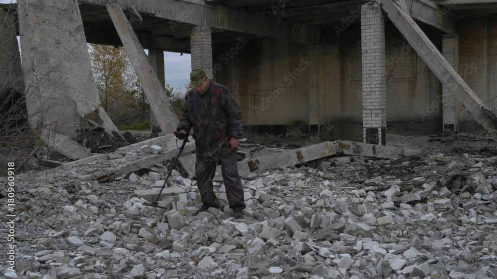 The soldier works with a mine detector in the ruins of houses in search of mines and explosives The soldier works with a mine detector in the ruins of houses in search of mines and explosives