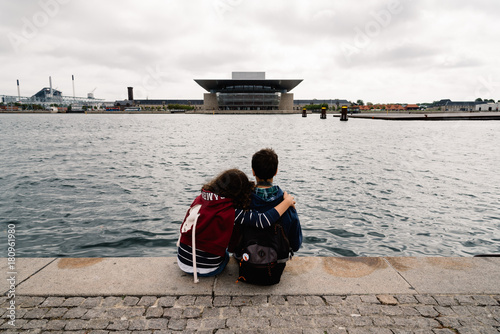 Photography A couple of young people embraced sitting looking at the waterfr