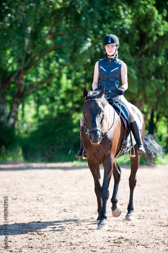 Young teenage girl riding horseback at equestrian school