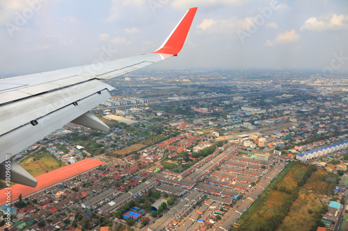 airplane wing over cityscape with red wingtip, airplane wing before landing