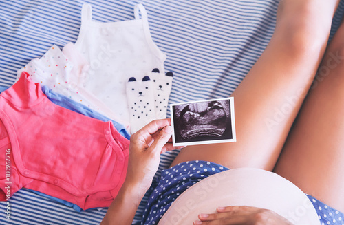 Pregnant woman holding ultrasound image.