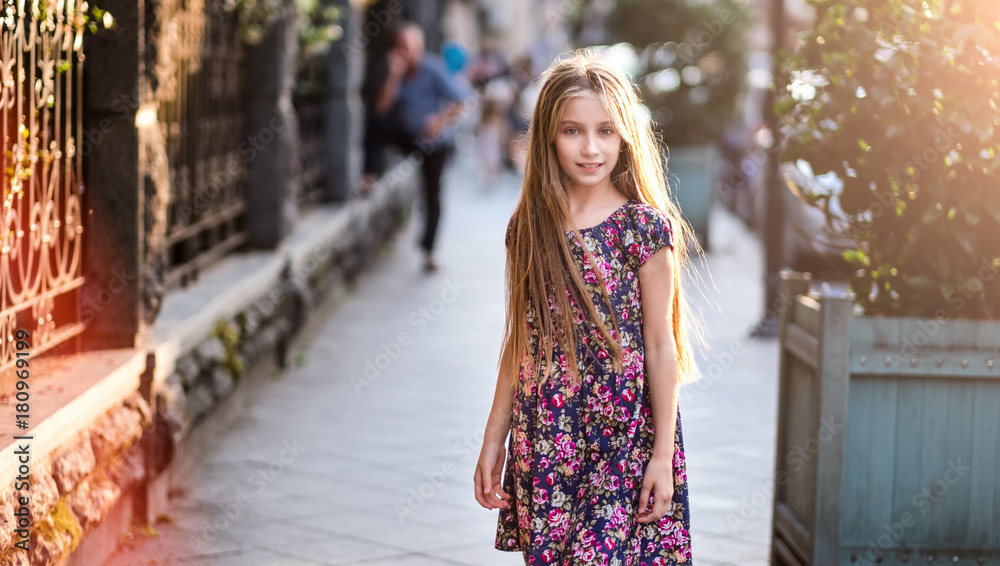 Fototapeta premium Beautiful little girl on a city street, evening fashion shot