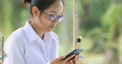 Happy asian womanhand holding mobile phone on swing chair with smile face. photo