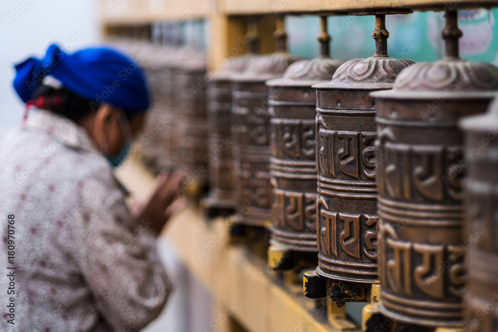Prayer wheels and woman who pray at Boudhanath Stupa in Kathmandu, Nepal