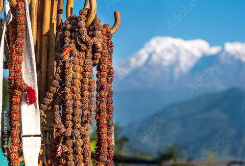 Rudraksha rosaries hanging on wooden hook in fronh of white top of mountain in Annapurna. photo