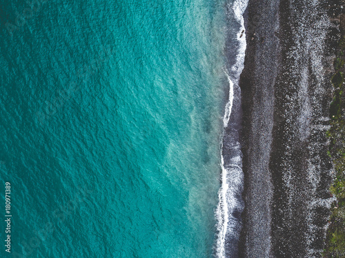 Aerial view of sea shoreline and dark pebble beach. View from above.