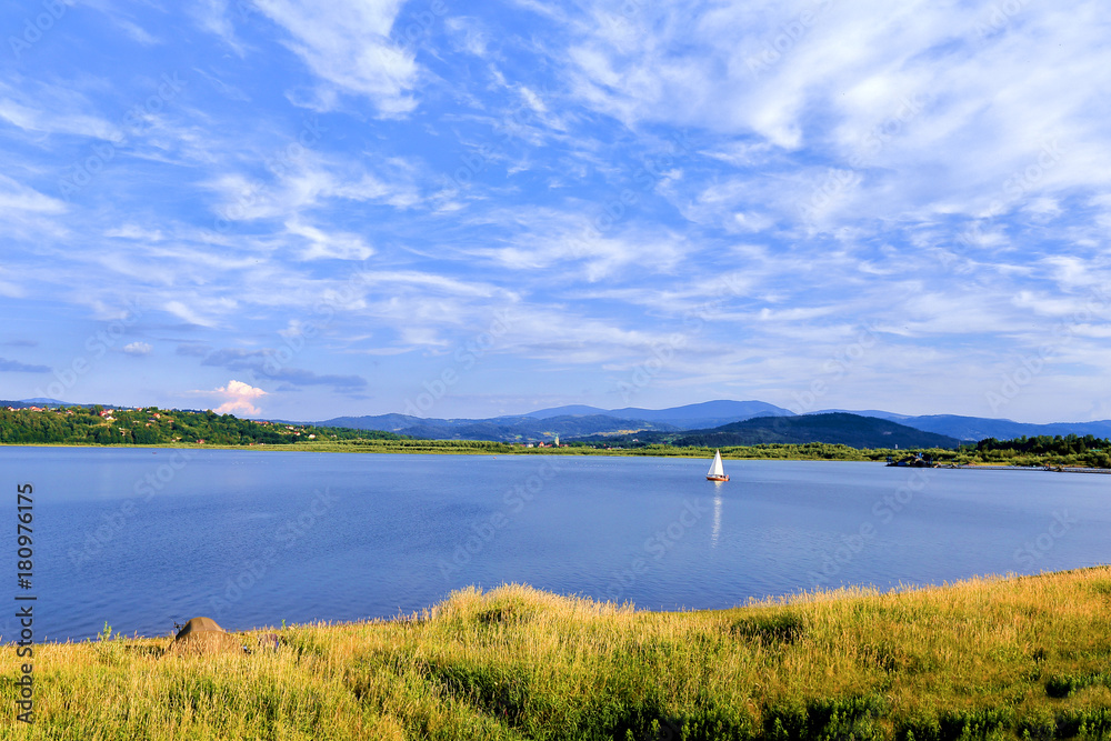 Sailboat on the beautiful lake under cloudy sky. Sailboat on the beautiful lake under cloudy sky.
