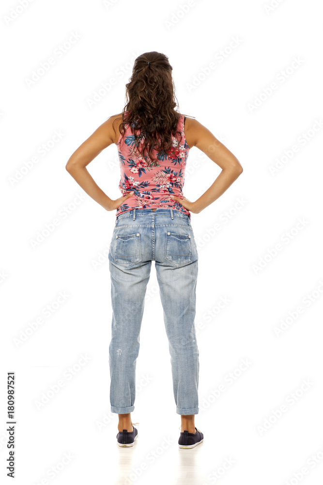 back view of young woman with torn jeans standing on white background