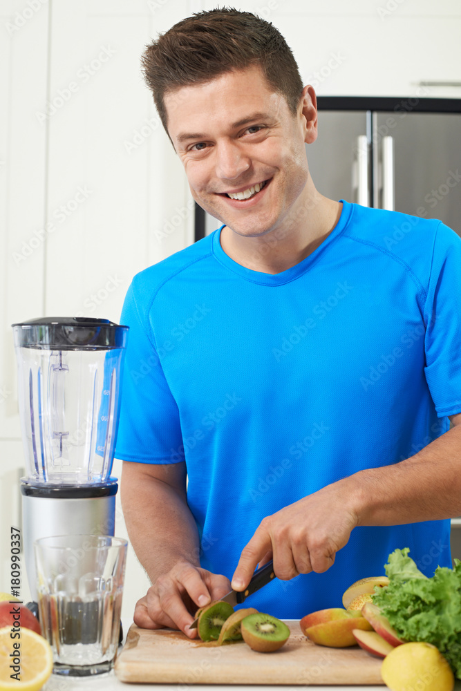 Male Athlete Making Juice Or Smoothie In Kitchen