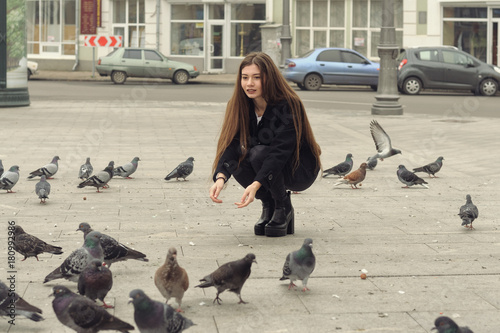 Beautiful girl squatted down and feeding the pigeons