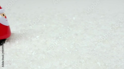 Cute Santa Claus windup dolly walks through the snow stopping in front of the camera