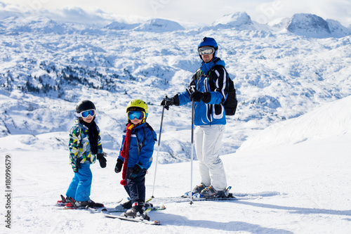 Father and two boys, skiing on a sunny day on a mountain summit in Austria resort