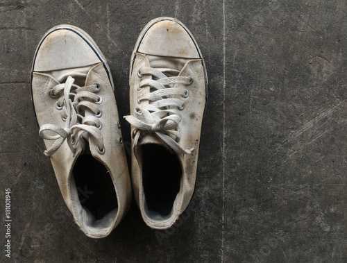 dirty and old white shoes on dirty cement ground