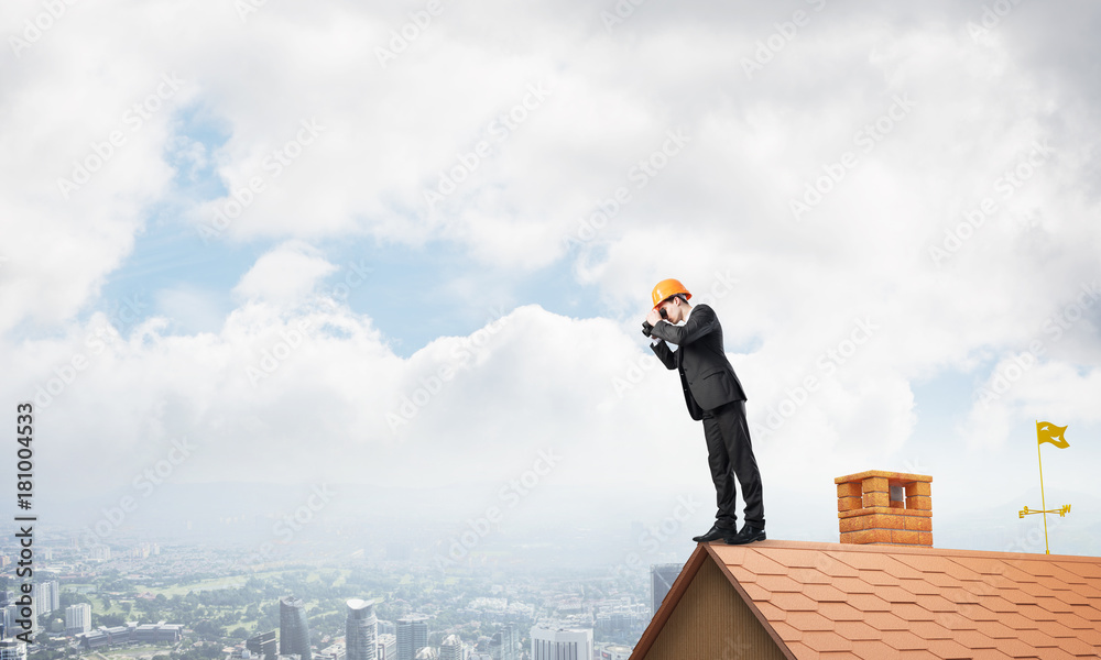 Engineer man standing on roof and looking in binoculars. Mixed media Engineer man standing on roof and looking in binoculars. Mixed media