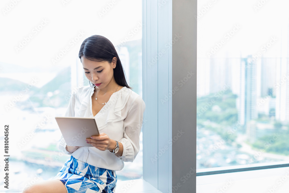 Woman sitting on windowsill using digital tablet Woman sitting on windowsill using digital tablet