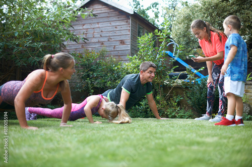 Family exercising in garden, doing push-ups photo