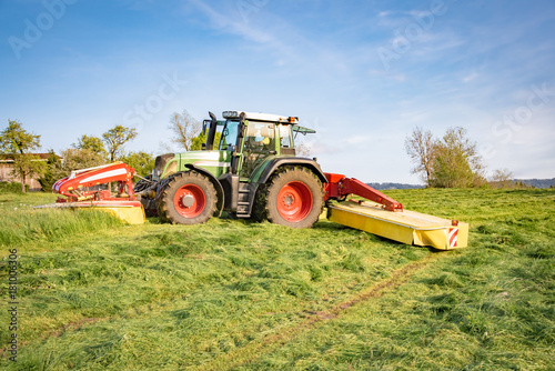 Traktor mit Front-  und Heckm  hwerk bei der Gras Mahd