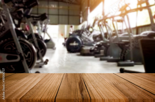 Wooden table on blurred background of fitness gym interior of modern club with equipment for your photomontage or product display. © snowing12