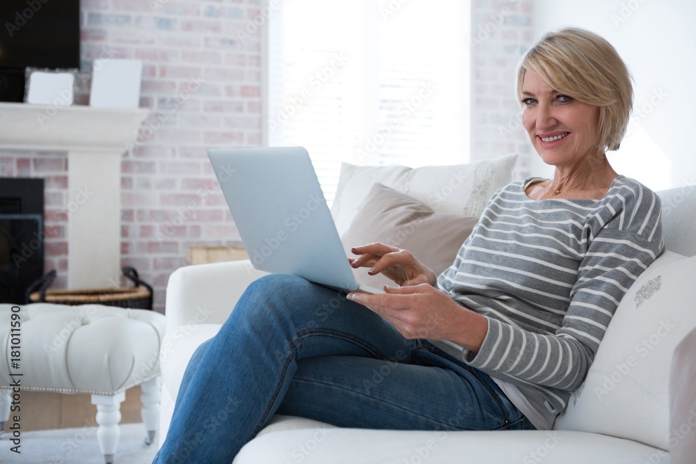Fototapeta premium Portrait of beautiful woman using laptop in living room