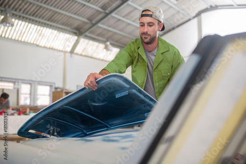 Man fitting car part in bodywork repair shop