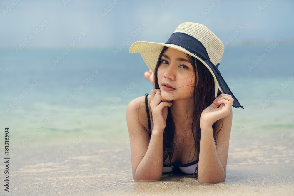 Beautiful woman wearing a hat lying on the beach