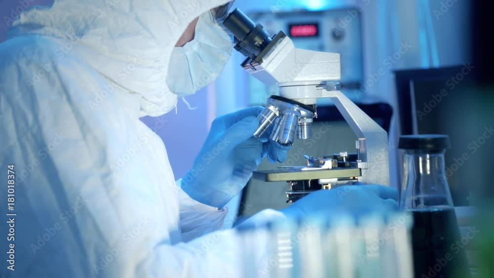 closeup virologist in hazardous lab using a microscope closeup virologist in hazardous lab using a microscope