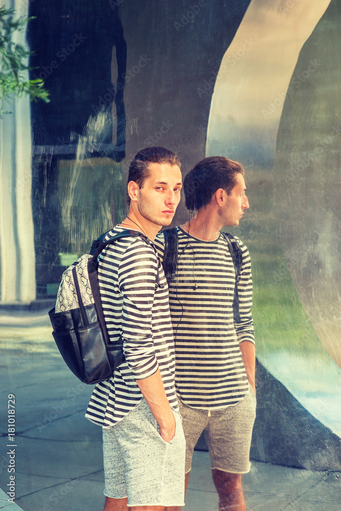 Young Russian Man wearing striped long sleeve T shirt, shorts, shoulder  carrying back bag, with hipster hairstyle, standing by metal mirror,  looking away, going to travel.. Stock Photo | Adobe Stock