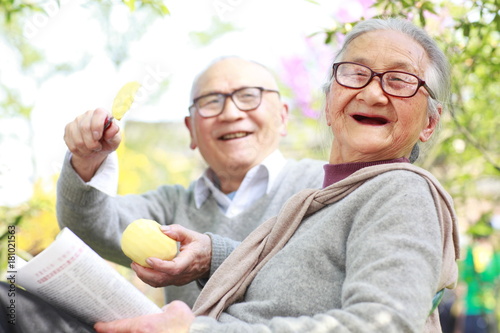 Happy senior asian couple reading book in the yard