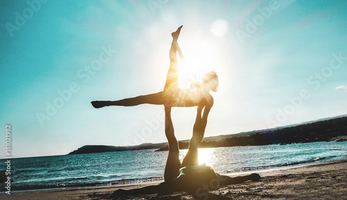 Silhouette young couple doing acro yoga outdoor on the beach