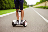 Close up. Men's legs in sneakers on the gyroboard. A man is riding on a road in a country park