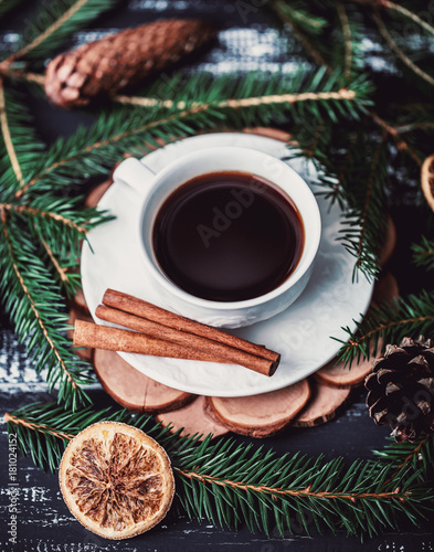 A cup of coffee with cinnamon on dark wooden background. A cup of coffee in christmas decorations 