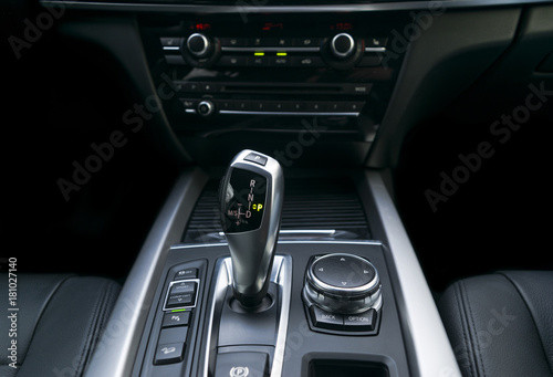 Automatic gear stick (transmission) of a modern car, multimedia and navigation control buttons. Car interior details. Transmission shift. © Aleksei