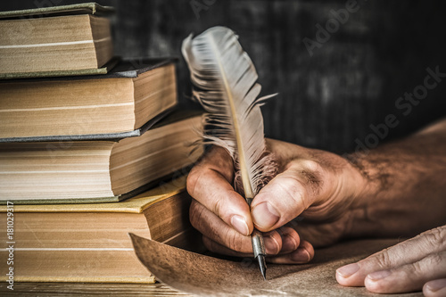 Man writing an old letter. Old quill pen, books and papyrus scroll on the  table. Historical atmosphere. Stock Photo | Adobe Stock
