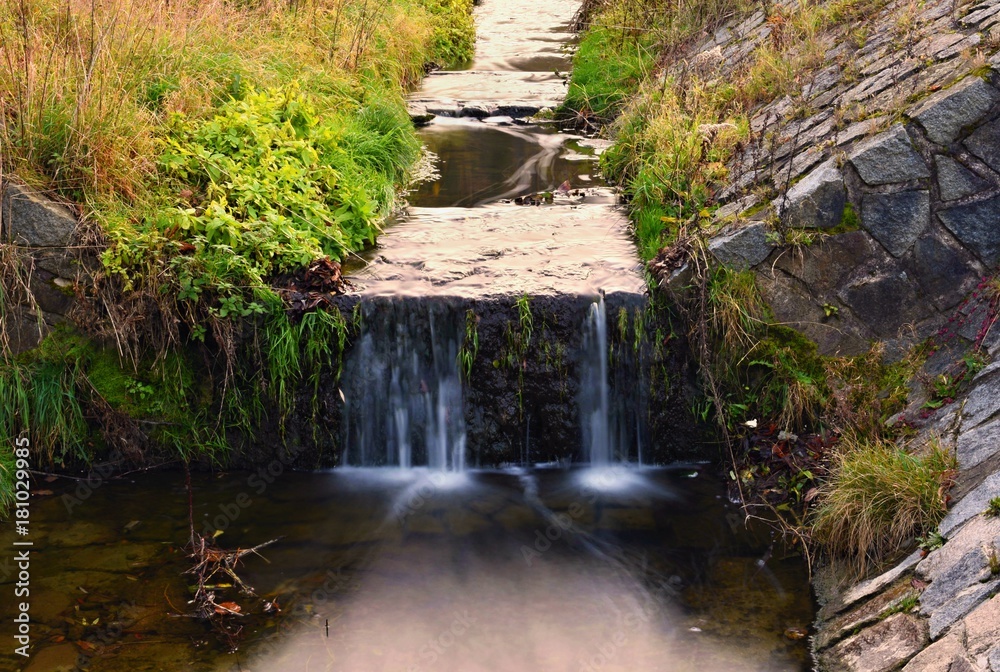 A beautiful clean brook in the countryside with a sink and running water.