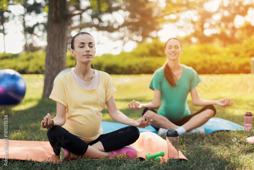 Fototapeta Naklejka Na Ścianę i Meble -  Pregnancy yoga. Three women sit on yoga mats in a lotus pose and smile