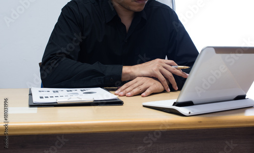 businessman working with business documents on office table with digital tablet computer and graph finance diagram in the background