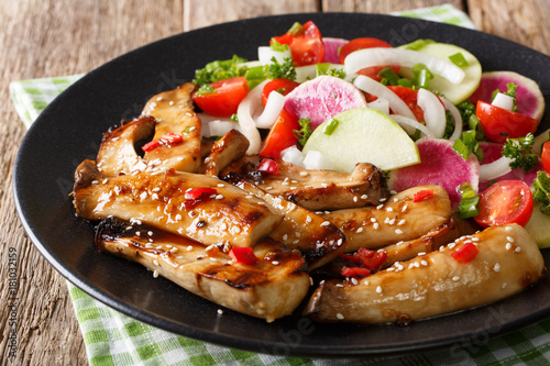 Delicious grilled king oyster mushrooms and salad of radishes and tomatoes close-up. horizontal