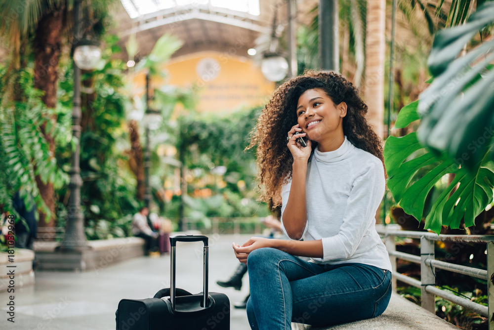 Young woman traveler with luggage talking on phone. Young woman traveler with luggage talking on phone.
