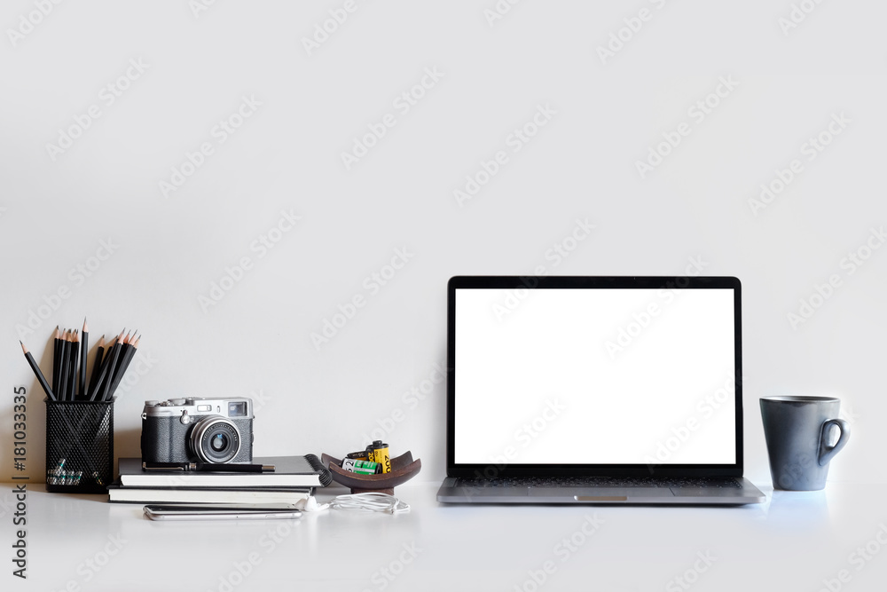 Mock up blank white laptop screen and camera with designer supplies on desktop.
