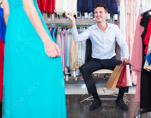 Man helping girlfriend to choose gown