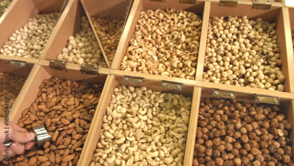 Peeled nuts and seeds in boxes.
The man's hand scoops the almonds with a shovel and pours it back into the box. Peeled nuts and seeds in boxes.
The man's hand scoops the almonds with a shovel and pours it back into the box.